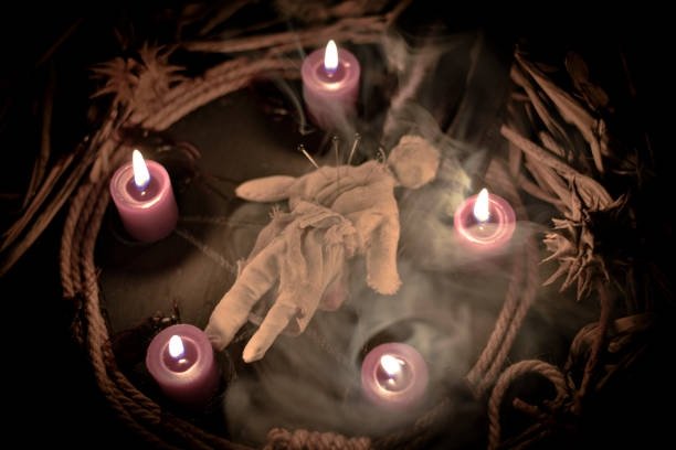 Muñeco ritual con alfileres rodeado de velas